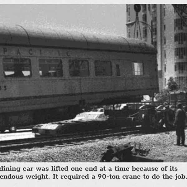 Black and white photo of a crane lifting a "Pacific" train car, with people watching nearby.