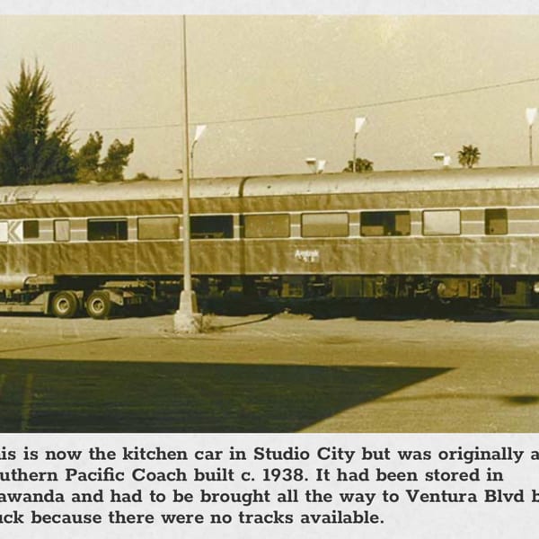 A vintage sepia-toned photo of a train car being transported on a flatbed truck.