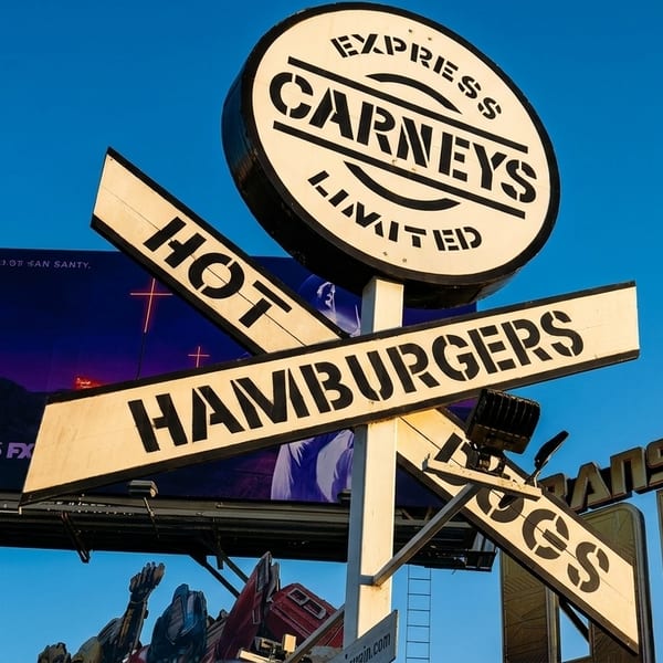 Carney's Express Limited sign advertising "Hot Hamburgers" and "Hot Dogs" against a clear blue sky.