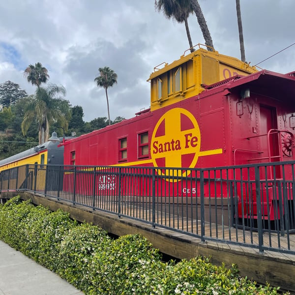 Red and yellow Santa Fe train cars, converted into a restaurant, sit on a raised platform.